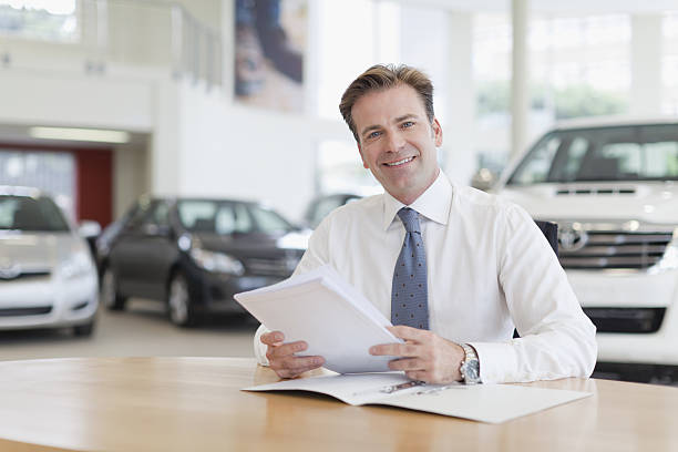 Car salesman with paperwork at desk  car salesperson stock pictures, royalty-free photos & images