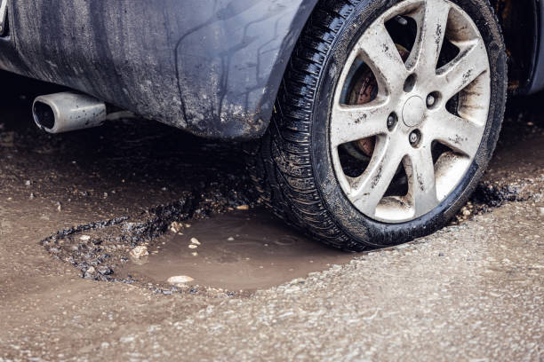 car tire in big pothole on the road stock photo