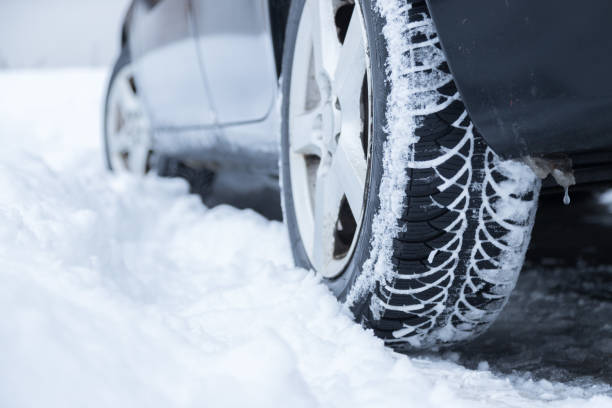 Car tire in winter on the road covered with snow, close up picture stock photo