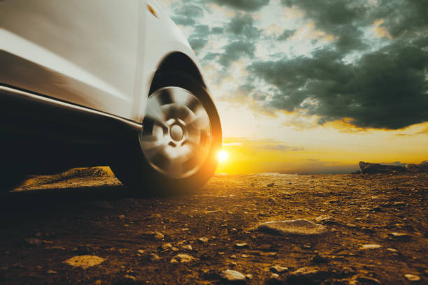 Car travel and adventur. Closed image of car wheels and tires on the ground and sunset sky sports utility vehicle stock pictures, royalty-free photos & images