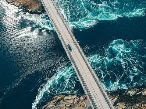 Torrents creating patterns in turquoise water underneath a bridge with a car traveling across it at Salstraumen near Bodo Norway