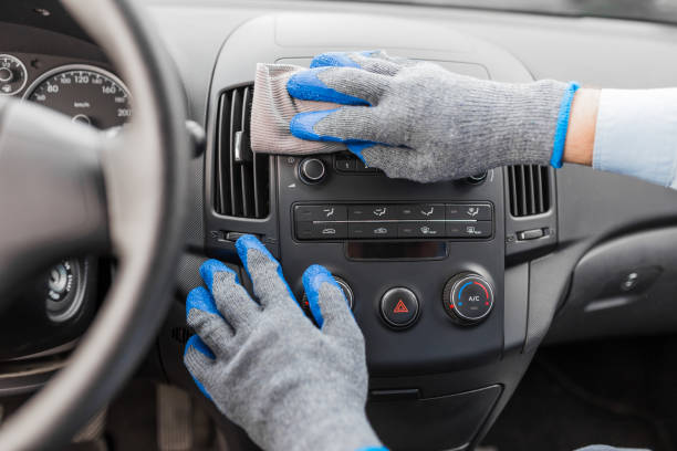 Car wash worker maintaining and detailing car interior console shine by using microfiber cloth. Car detailing or valeting concept. stock photo