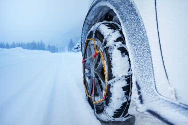 Car with snow chains for tire on snowcapped road stock photo