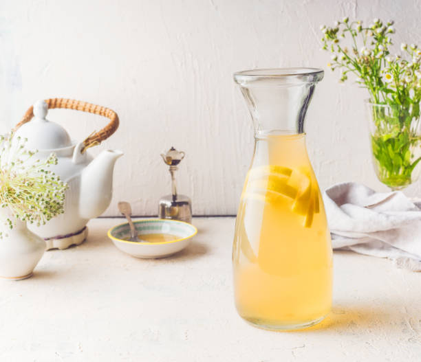 Carafe with white tea citrus lemonade drink on white kitchen table. stock photo