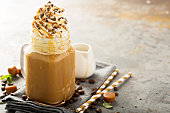 Caramel iced latte with whipped cream and syrup on light background