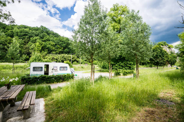 Caravan trailer parked in a green park on a clear sunny day, cloudy blue sky. Dinant, Belgium stock photo