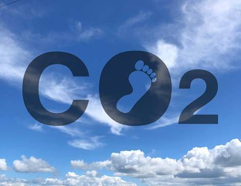 Carbon Dioxide and carbon footprint concept against a bright blue sky with light cloud, United Kingdom