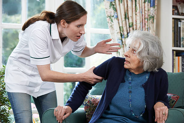 Care Worker Mistreating Senior Woman At Home stock photo
