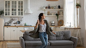 Carefree happy single young attractive woman dancing alone in modern kitchen interior, independent active lady having fun at clean home listening music enjoying freedom weekend time lifestyle at home