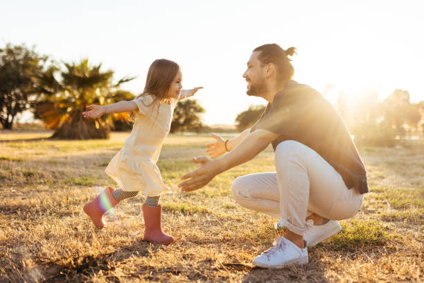 Carefree young father and daughter hugging in spring day. Happy young father and daughter having fun while running in spring day at the park. fathers day stock pictures, royalty-free photos & images