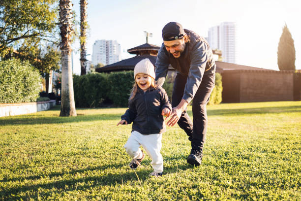 Carefree young father and daughter walking in spring day. Happy young father and daughter having fun while running in spring day at the park. fathers day stock pictures, royalty-free photos & images