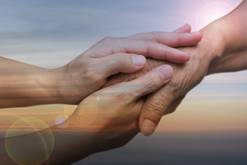 Caregiver Carer Hand Holding Elder Hand In Hospice Care With Sky Sunset ...