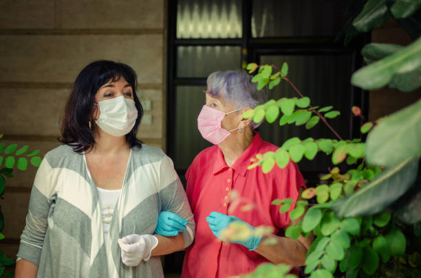 A caregiver took an elderly client out for a walk. Both wear protective face masks. stock photo