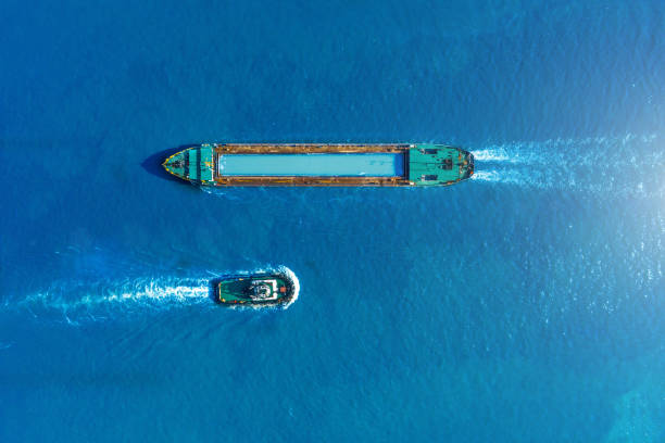 Cargo ship barge and tugboat sail to meet each other in the seaport of the port, aerial view. Cargo ship barge and tugboat sail to meet each other in the seaport of the port, aerial view barge stock pictures, royalty-free photos & images