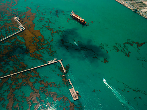 This is a container ship heavy with cargo on the Atlantic ocean. An oil spill and algae formation is seen all over the path of the ship as it was travelling beside an oil depot in Lagos Nigeria.