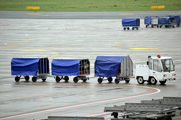 Cargo transportation - airport Horizontal view of cargo transportation on the airport - car tows luggage-carts. luggage cart stock pictures, royalty-free photos & images