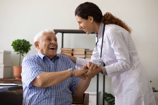 Caring female doctor support and cheer elderly man stock photo