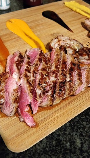 Shot of freshly made sliced steak served on of a wooden chopping board