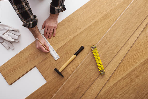 Carpenter installing a wooden flooring Carpenter installing a wooden flooring and measuring with a precision ruler, top view hardwood stock pictures, royalty-free photos & images