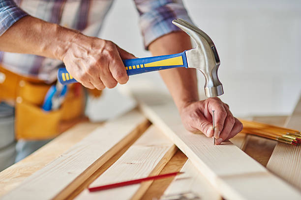 Carpenter with hammer hitting nails stock photo