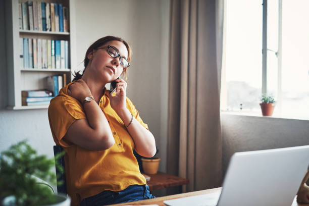 I carry so much tension in my neck Cropped shot of an attractive young businesswoman sitting alone in her home office and feeling stressed while using her cellphone emotional stress stock pictures, royalty-free photos & images