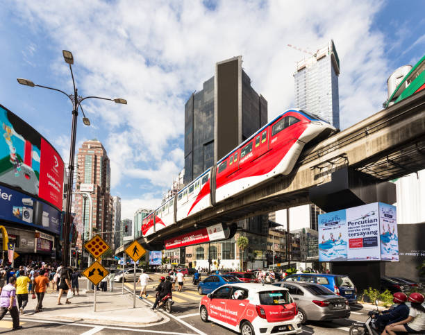 Cars and a monorail train rush through the Bukit Bintang intersection in the Golden Triangle area in the heart of Kuala Lumpur in Malaysia capital stock photo