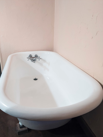 Large, empty cast iron claw foot bath tub in a clean, white bathroom