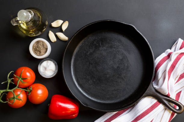 Cast Iron Skillet with copy area on black background with ingredients stock photo