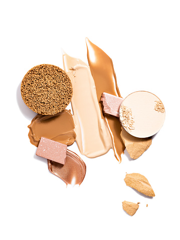 Casual make up products. Spills and smears of makeup foundation, eyeshadow, face powder and shimmering powder isolated on white background. Beauty, professional makeup, contouring, fashion concept.