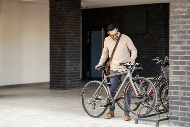 A casual businessman parking his bicycle outdoors. stock photo
