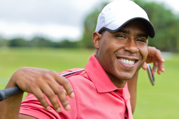 Casual close-up portrait of a happy African-American golfer with his golf club resting on his shoulders behind him stock photo
