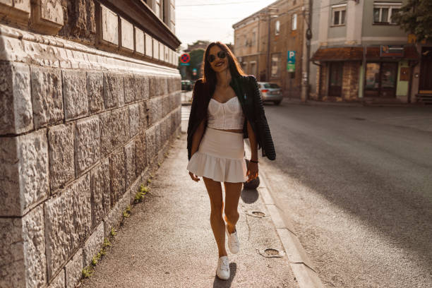 Casual dressed woman walking in the city street on a sunny day stock photo