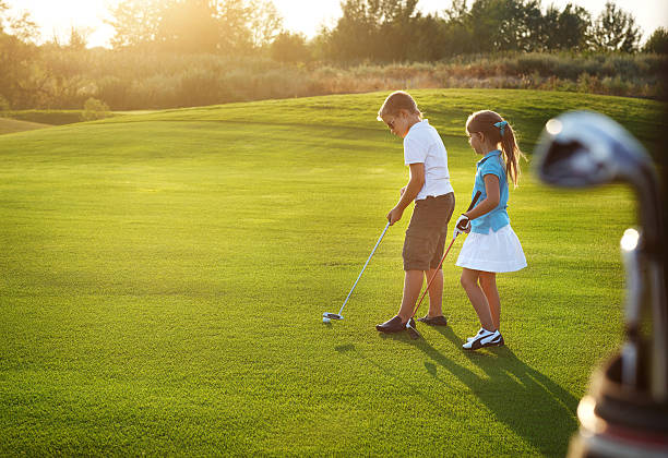 Casual kids at a golf field holding clubs stock photo