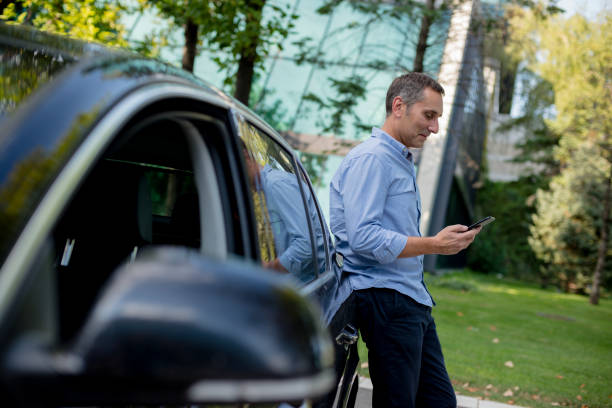 Casually dressed businessman using his smartphone on the parking Portrait of a casually dressed man leaning against a black car and using his smartphone in the street cchaturbate stock pictures, royalty-free photos & images