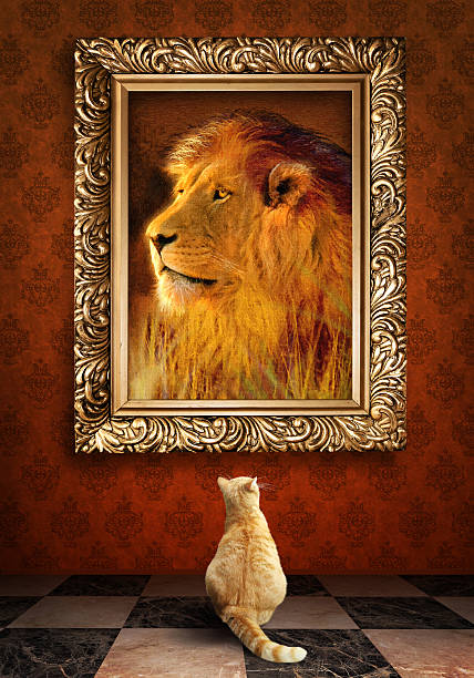 Cat looking at a portrait of lion in golden frame. stock photo