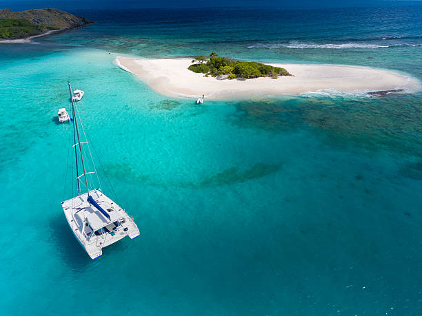Catamaran at anchor in front of deserted island Aerial view of a atamaran at anchor in front of a tropica catamaran stock pictures, royalty-free photos & images