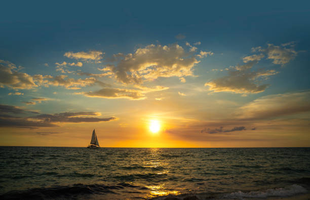 Catamaran navigating at sunset in Naples beach stock photo