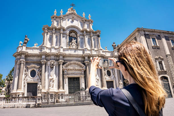 Catania, Sicily, Piazza del Duomo with Duomo of Saint Agatha, woman tourist takes a picture with smartphone on a summer sunny day stock photo