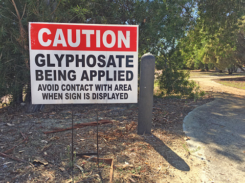 Cation Glyphosate being applied. Outdoor sign on city park path. No people. Copy space