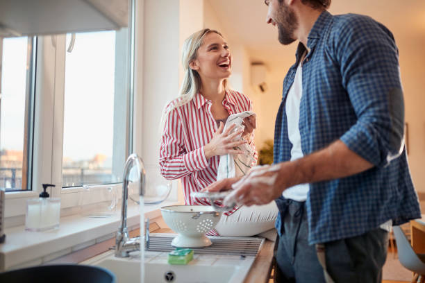 caucasian adult couple in love having fun while washing dishes stock photo