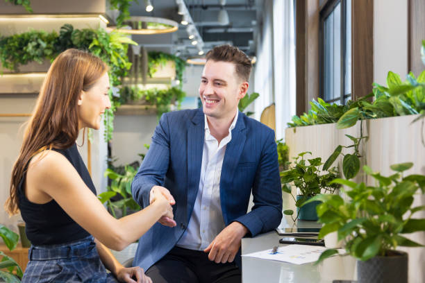 Caucasian businessman is shaking hand while working in the green eco friendly modern working space surrounded by air purifying house plant stock photo