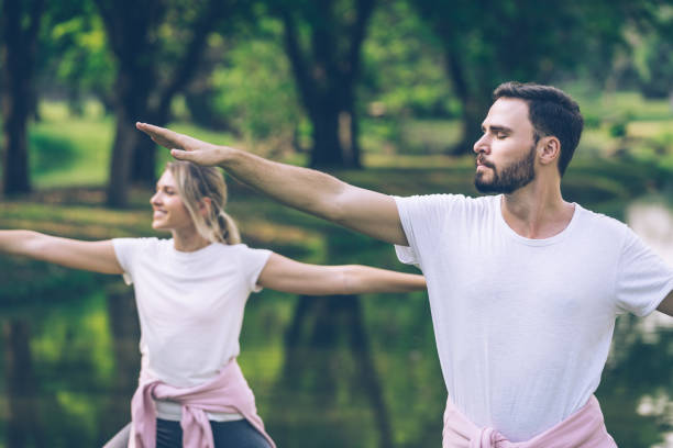 Kaukasisch paar in sportkledingpraktijk Yoga in Openbaar park​​​ foto