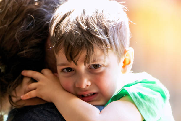Caucasian Crying little boy embracing his mother looking at the camera stock photo