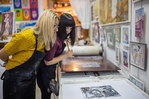 Mid-adult Caucasian female artist, observing the lithography art they made in their art workshop