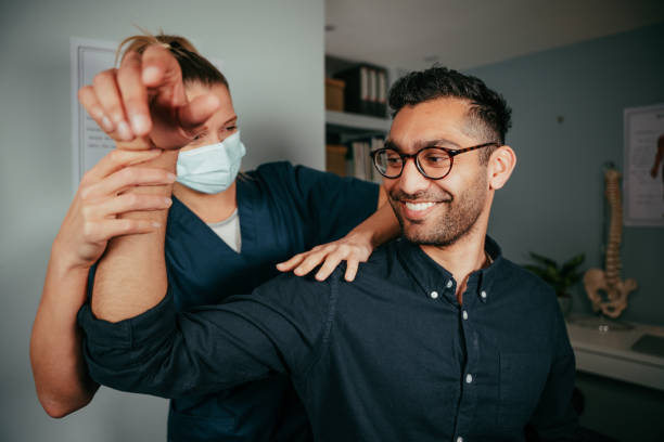 enfermera femenina caucásica que ajusta el brazo lesionado del paciente masculino - nurse talking to camera fotografías e imágenes de stock