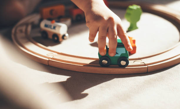 caucasian kid is playing with toy train on the railway on the floor stock photo