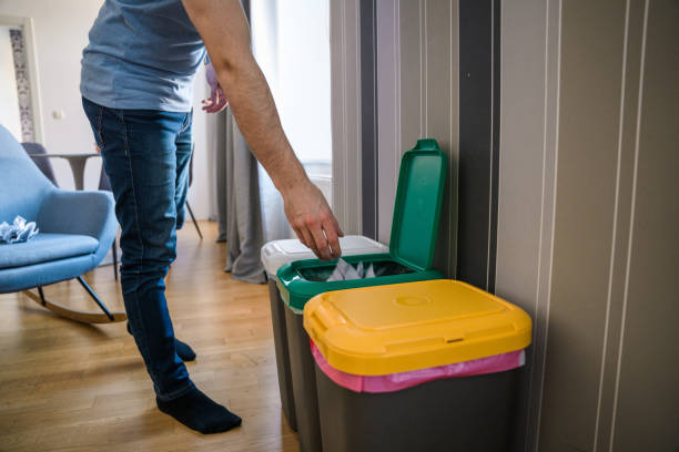 Caucasian Mid Adult Man Recycling Paper and Putting into a Garbage Bin Caucasian mid adult man is putting paper into a garbage bin at home. He is recycling trash. junk removal stock pictures, royalty-free photos & images