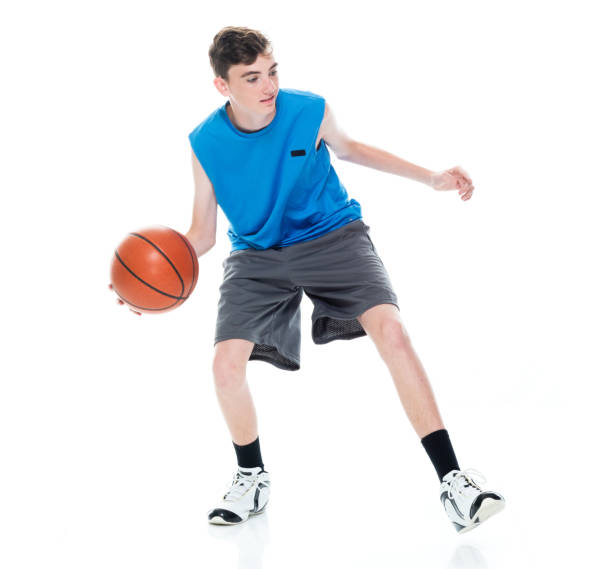 Caucasian young male basketball player in front of white background and holding basketball - ball and using sports ball stock photo