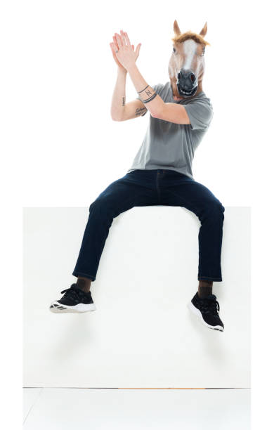 Caucasian young male resting in front of white background wearing mask - disguise Full length of aged 20-29 years old with blond hair caucasian young male resting in front of white background wearing mask - disguise who is excited and clapping and wearing horse mask horse mask photos stock pictures, royalty-free photos & images
