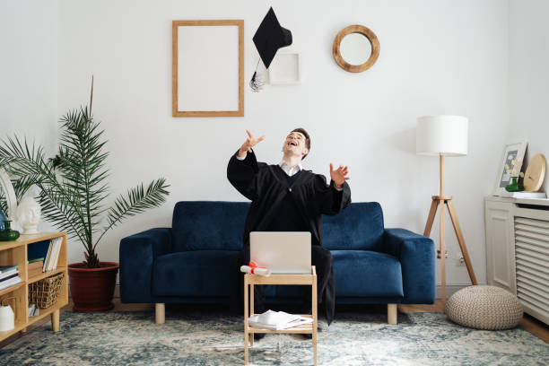 Caucasian young man feeling very excited to receive his bachelors degree Education, graduation and people concept - happy male student with diploma and laptop at home showing his emotions bachelor’s degrees online stock pictures, royalty-free photos & images